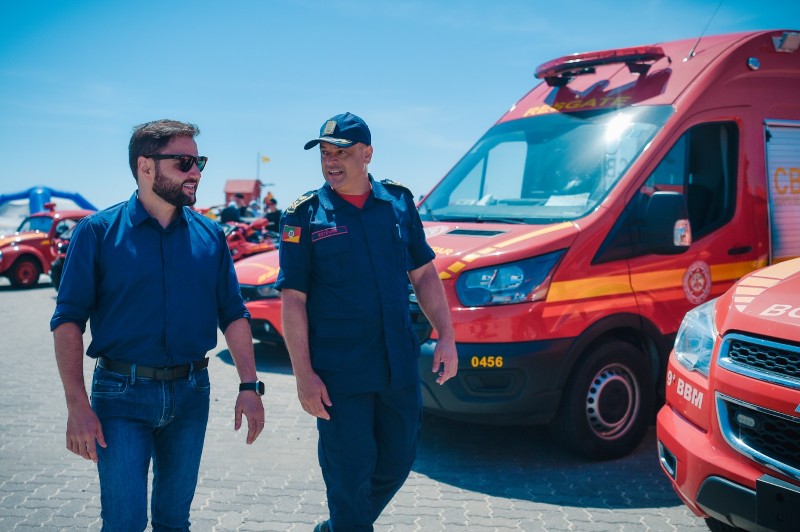 Dois homens caminham em frente à viaturas do Corpo de Bombeiros Militar do Rio Grande do Sul